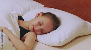 Cute young girl sleeping in bed. Lovely girl smiling while sleeping in bedroom. Sleeping, dreaming concept