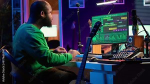Creative songwriter singing a melody and playing guitar, signal processing technology with digital audio software. Artist producer creating music with acoustic instrument and console. Camera A.