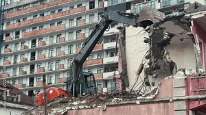 Excavator demolish or remove old ruined building in rainy day. Old house demolition on construct cite for renovation new housing in modern city.