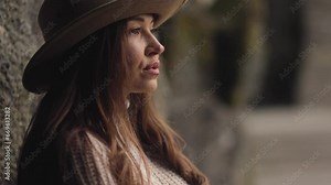 A beautiful lady in a cowboy hat, face close up in slow motion, beautiful facial features, lips, and eyes. Hair and a sultry gaze. Beauty and cinema concept. Warm colors. Woman. Cinematic
