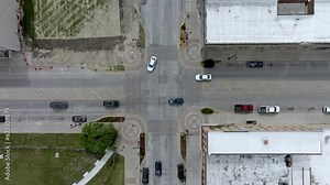 Intersection in downtown Marshalltown, Iowa with traffic moving and drone video overhead moving down.