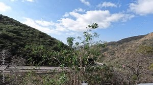 Side driving view of road work ahead sign on curving Potrero Canyon Road in rural Ventura County California.