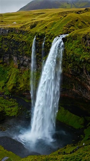 Seljalandsfoss is one of the only waterfalls in Iceland you can walk behind 💧 The path takes you into a misty cave-like view from inside the cascade. 🥾 Traveler tip: Wear a rain jacket—it’s breathtaking, but very splashy! Video by Alex Kassner | @alex.kassner | Guide to Iceland