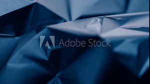 The crumpled dark blue paper exhibits intricate creases and folds, creating an abstract textural backdrop ideal for artistic or design purposes.