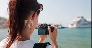 Woman traveler take photo of cruise ship. Cinematic and inspiring travel blogger live motivational adventure. Happy young woman on summer vacation