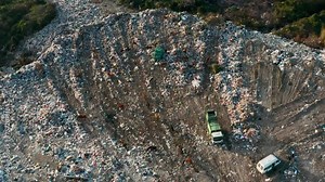 Aerial view of garbage pile in trash dump with dump track unload garbage at landfill. Biohazard for ecosystem and healthy environment concept. Environmental pollution and ecological disaster