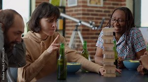 Diverse group of friends enjoying game with wooden tower blocks, playing competition with square pieces and cubes on construction. Happy people having fun with board games at home.