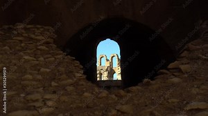 View of the internal facade of the Amphitheater through a stone window. Ancient Roman ruins. Ancient Amphitheater located in El Jem, Tunis. Historic Landmark.