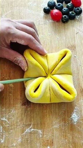 Hand folds patterned yellow dough on floured board