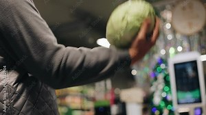 The seller in the store throws up and catches a cabbage. The camera captures the action in slow motion