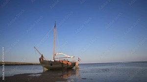 Timelapse of the rising tide showing a classic sailing boat anchoring on the tidal mudflats of the Wadden Sea, Holland