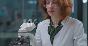 biotechnologist woman is working in research laboratory, viewing sample in microscope, portrait of expert person
