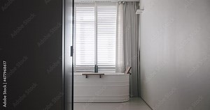 Transparent sliding door opens inside the modern bathroom, minimalist bathtub