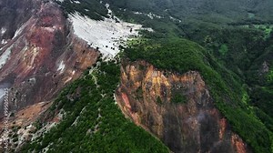 Aerial video captures the diverse landscape of Mount Papandayan, featuring the striking Hutan Mati (Dead Forest) with its barren trees, winding paths, lush surrounding forest, and dramatic cliffs