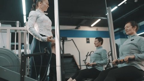 clip-4003190639-personal-trainer-encouraging-senior-woman-on-rowing