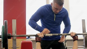 Paurlifting. The sports man. Gym. The man lifts heavy weight lying on a back. Training. The man does exercises. Bodybuilder lifting heavy barbell weights. Close up. The man in the gym. The trainer