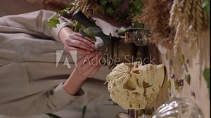 A vertical shot of a woman performing occult rituals. Occult and esoteric witch still life. Halloween background with magic objects. Mystic witchery background with weeds.