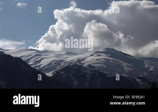 Carpathian Mountains snowy range under towering clouds, time lapse weather shifting above ridges. Tatras white summits meet rolling cumulus while rapid motion reveals changing sky across highlands. carpathians, storm clouds, sunlight, fog.