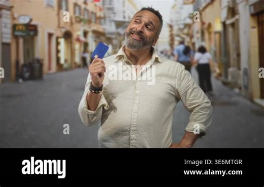 Man holding creditcard up in street with beard and rolled sleeves showing card to camera; confidence travel leisure Stock Video Footage - Alamy
