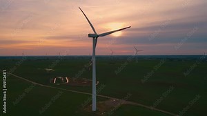 Large windmills turbines produce eco electric with bright orange sunset and blue sky drone view. Electricity, ecological saving and alternative power source