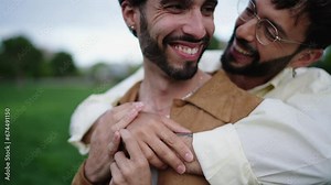 Two men embrace in park, share tender moment of laughter, male partners faces aglow with joy and mutual affection. Happy gay LGBT couple hugging and smiling, immersed in a moment of happiness and love
