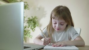 Homework With Laptop Computer.Focused Little Cute Kid Studying at Table doing homework Preschooler Girl Drawing on Paper Elearning Remote Education Distance course