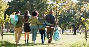 Group, plastic bag or people in park walking for waste management or recycling in community service. Back view, teamwork and volunteers cleaning garbage, junk or rubbish for nature sustainability