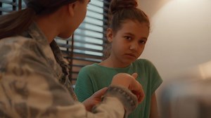 Woman helping girl doing homework at table