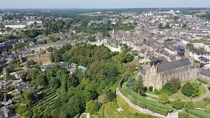 Scenic view from drone of upper town of Fougeres overlooking Flamboyant Gothic parish church of St. Leonard with fortified Chateau in background, France. High quality 4k footage