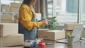 Success online business,SME online,sale page and e-Commerce concept.Smiling happy young Asian woman entrepreneur receiving phone call for new sales order among boxes of product with laptop at home.
