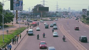 Premium stock video - Downtown kinshasa skyline behind boulevard lumumba traffic - congo drc