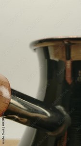 Authentic coffee turk cezve with wooden handle on the kitchen table with a white background. Macro Dolly shooting. Vertical shot.