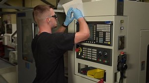 Man reading a technical drawing and programming a CNC milling machine in workshop