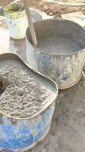 Mixing wet concrete slurry in large buckets at a construction site