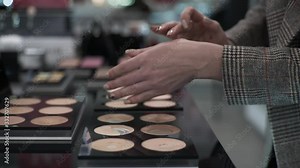 emale buyer chooses makeup foundation tests foundation on her hand to match her skin tone at a cosmetics store