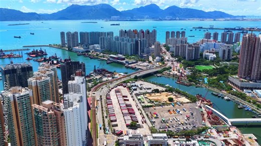 Aerial skyview of Tuen Mun subway extension project in Hong Kong, featuring elevated railway construction along Tuen Mun River and road, new station development and temporary work platforms