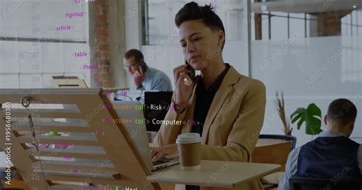 Woman at standing desk answering call about security while typing laptop and watching code overlay