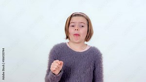 A young girl is spitting out the pickle that she was chewing. She doesn't like it.