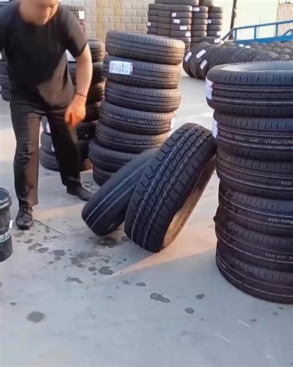A worker uses lubrication & body weight to force three tires into one. This saves shipping space therefore reducing costs.