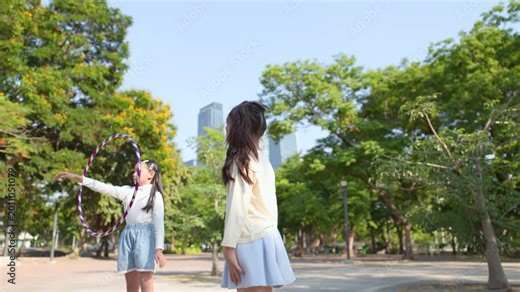 Two Young Thai Girls Playing With Hula Hoop In Bangkok Park