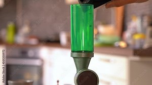 Person filling column of powder measure for home reloading of rifle cartridges - Static clip with closeup of powder measure and blurred kitchen in background