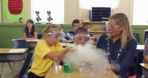 Download Teacher and students doing science experiment in school classroom for free