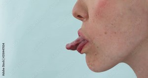 Woman smiling and showing tongue side view. Girl with her tongue out on a blue background