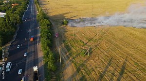 Red firetruck go straight to epicenter of agricultural field fire with smoke near highway with lot of cars. Emergency case for danger mission and rescue nature saving concept