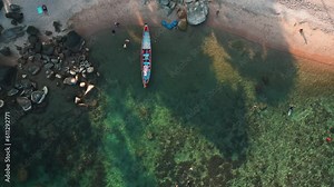 Top view tropical beach with clear turquoise sea water and reefs suitable for diving and snorkeling. Tourists rest on the beach. Boat floats next to the beach. Tropical exotic summer holidays concept