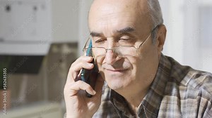 The old man is talking on the phone. Close-up old man talking on the phone, listening and telling troubles.
