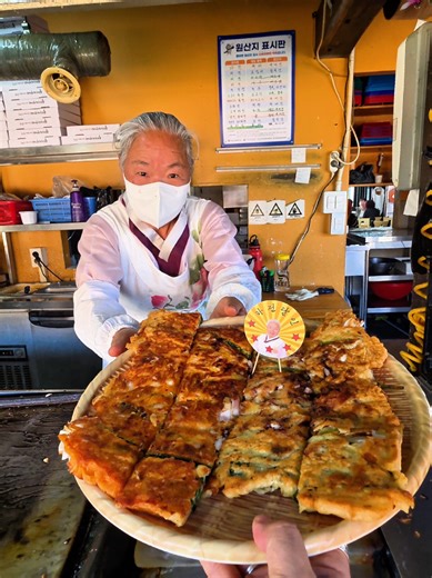 Giant Green Onion Pancake in Korea 이거 그냥 파전 아님, 흑백요리사 나온 파전 할머니가 부쳐주는 전설급 파전임🔥 철판 위에 쪽파 산처럼 깔고 해물 미친 듯이 올려서 겉바속촉 비주얼 그냥 압살🤯 한입 먹는 순간 바삭한 가장자리 촉촉한 속재료 조합 제대로 터짐🥢💥 요즘 흑백요리사 성지순례 로컬맛집 찾는 사람들 사이에서 뜨는 아산 찐맛집 인정👀 📍 위치 : 충남 아산시 송악면 외암로 1030-14 14동 1층 🏡 매장명 : 외암파전 상전 ⏰ 운영시간 : 방문 전 확인 권장 🚃 가까운역 : 아산역 차량 약 30분 💵 가격 : 해물파전 ₩20,000 / 반반파전 ₩22,000 / 산채비빔밥 ₩10,000 This is not just Korean pancake—this is the viral grandma from Culinary Class Wars🔥 Massive green onions loaded seafood hit the hot iron 