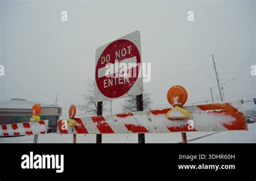 Red Do Not Enter sign stands behind road closure barriers during snowy winter conditions. traffic restriction, blocked access due to weather or road work. Close side POV view. High quality 4k footage Stock Video Footage - Alamy