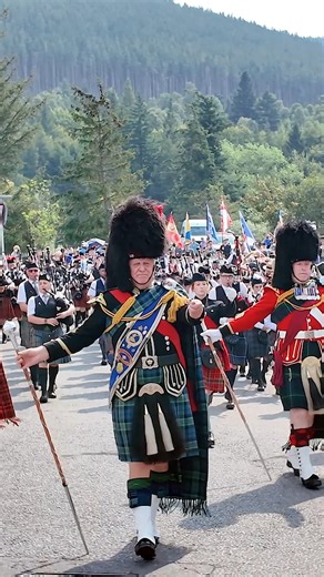 Drum Majors lead the combined Pipe Bands as they marched over the river Dee into Ballater playing Flett from Flotta, Wings and Scotland the Brave. This was on Thursday 14th August 2025, as the bands marched through the town to the 2025 Ballater Highland Games in Deeside, Scotland. The leading Drum Major here was Bill Barclay, followed by Derek Dean, Neil Jamieson, Rob Brownfield, Nick Stables, Ellen Archer and Andy Curwen. The band staking part included Towie Pipe Band, Dufftown & District Pipes