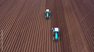 Tractor sowing seeds with a seeder driller in a field. Top view of tractor sowing and cultivating field.